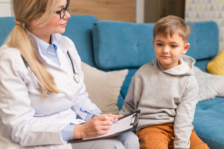A family doctor examines a little boy at home. Pediatrician girl treats a childの写真素材