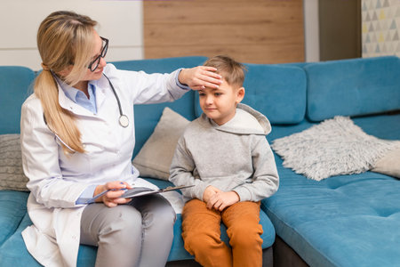 A family doctor examines a little boy at home. Pediatrician girl treats a childの写真素材
