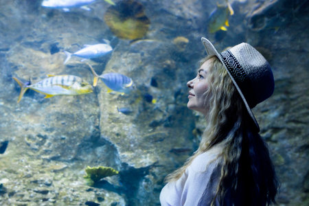 A young woman touches a stingray fish in an oceanarium tunnelの写真素材