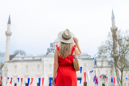 A beautiful travel blogger girl in a long red dress and a straw hat is photographed at the ancient sights in Istanbul in Turkeyの写真素材