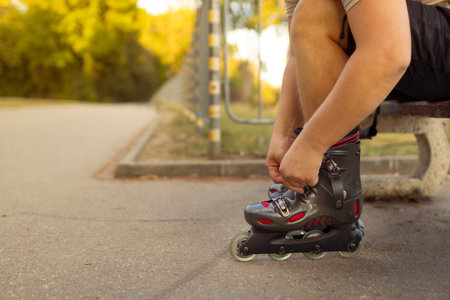 Legs of young man putting on roller skates in the park