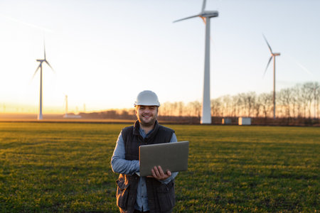 Electrical engineers working at wind turbine power generator station with laptop computerの写真素材
