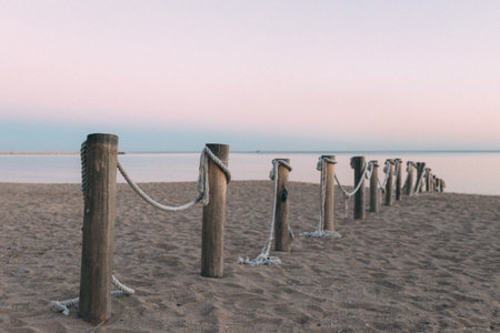 A row of wooden posts with rope tied to them on a beachの写真素材