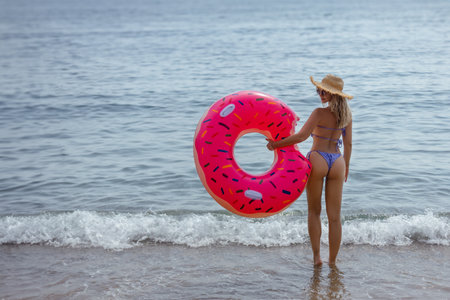 Athletic young woman in a bikini with an inflatable swim ring. Outdoor lifestyle picture on a sunny summer day.の写真素材