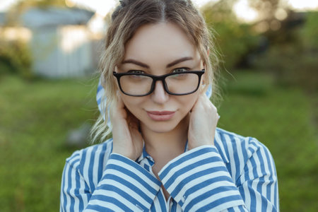 Optics for vision and fashion. A girl looks at the camera on her glasses. Beautiful look through the frames close-upの写真素材