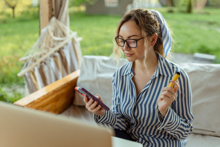 A beautiful girl smokes a cigarette and uses a smartphone. Event Organizerの写真素材