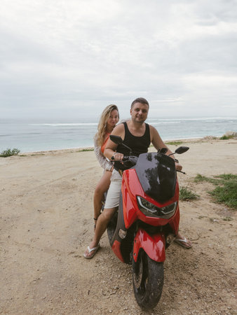Young couple riding a scooter near the sea