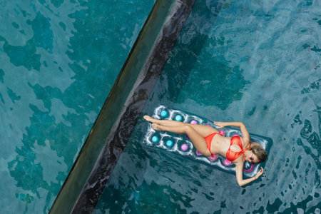 Enjoying sunbathing. Tropical vacation concept. Top view of young woman on inflatable mattress in...