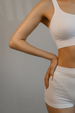 Full lenght portrait of beautiful young fit, slim woman in white underwear, lingerie posing against studio background. Concept of natural beauty, health and body care, spa, anti-cellulite, femininityの写真素材