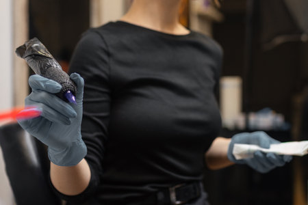 tattoo artist in gloves holding a tattoo machine during a session, preparing tools in a professional studio environment.の写真素材