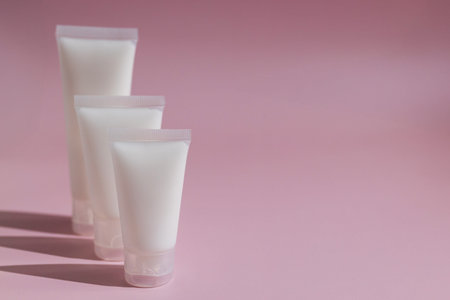 Minimalist skincare mockup with blank cosmetic tubes on soft pink background, perfect for beauty...