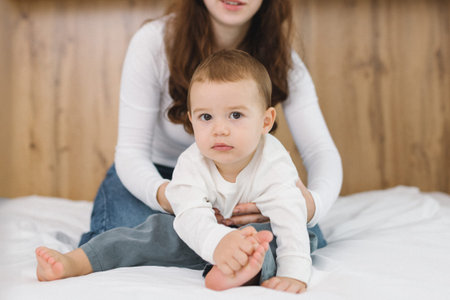 Young mother playing with her baby at home, enjoying a warm and cozy family moment full of...