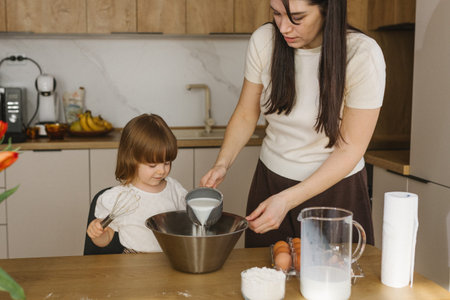 Mother and little daughter baking together in modern kitchen at home, happy family cooking and...