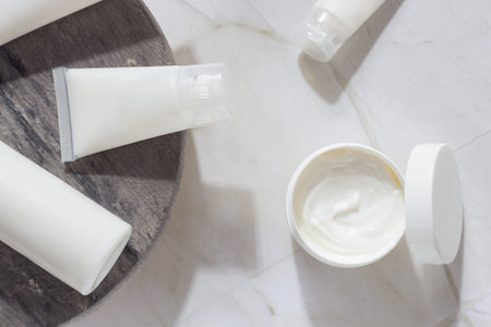 Minimal skincare products with cosmetic cream jar and tubes on marble surface, beauty routine and...