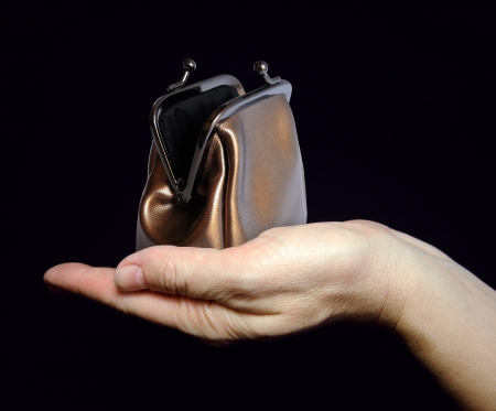 Female hand holds an empty change purse on black background  Asking for help  の写真素材