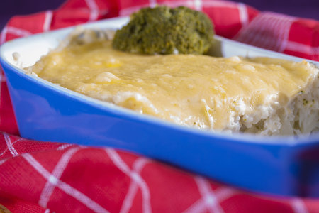 Fresh baked a Cauliflower with a yeloow cheese in a blue dishの写真素材