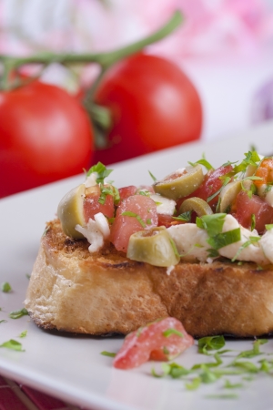 Traditional Italian food - Bruschetta  Peace of a grilled bred with tomato, olives and white cheese - mozzarellaの写真素材
