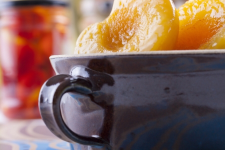 Taste of summer at your table - sweet peaches in a syrup in a clay bowlの写真素材