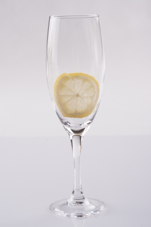Simple photo of a white wine glass with a slice of lemon over a solid bright backgroundの写真素材