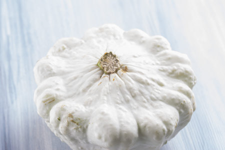 Close up photo of edible vegetables - a Pattypan squash on a solid light blue wooden tableの写真素材