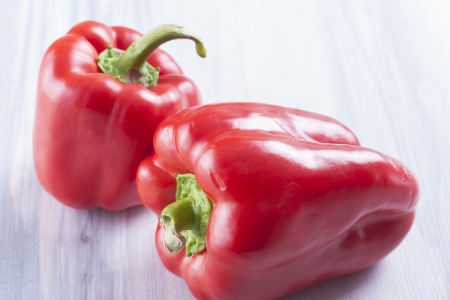 Close up photo of edible vegetables - a red bell pepper on a solid light blue wooden tableの写真素材