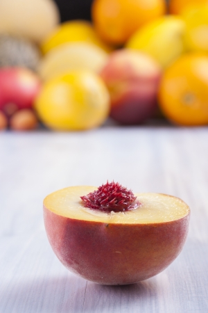 Close up photo of edible fruits - a peach with other full colors fruits in the background on a solid  bright blue wooden tableの写真素材
