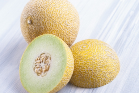 Close up photo of edible fruits - a melon on a solid  bright blue wooden tableの写真素材