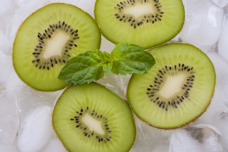 Composition of fresh green kiwi fruit slices with ice cubes and mint herb leaf.の写真素材