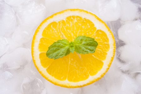 Composition of fresh orange fruit slices with ice cubes and mint herb leaf.の写真素材