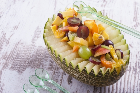Colorful close up photo of the fresh sliced multiple fruits placed into a half of the melon fruit.の写真素材