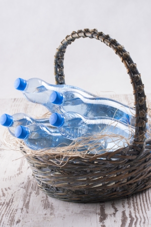 Couple of sparkling water blue bottles in a wooden basket on a bright wood background,の写真素材