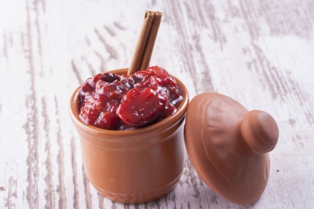A close up photo of sweet fruits dessert - plum jam, also known as plum powidl in a clay cup.の写真素材