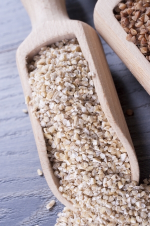 Close up photo of a eco raw food in the spoon - light brown pearl barley placed on a dark wooden background の写真素材