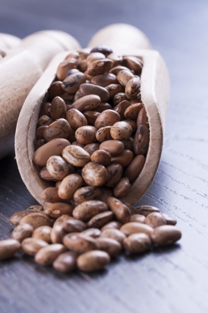 Close up photo of a beans in wooden scoop - brown pinto beans placed on a dark wooden background.の写真素材