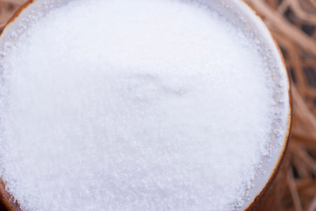 Close up photo of a food ingredients in a clay cup - small pieces of a table salt placed on a wooden...