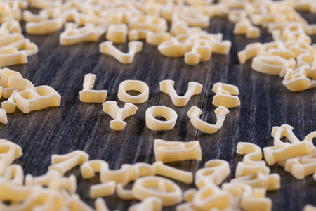 Close up photo of a letter noodles - Love you text placed on a dark wooden background.の写真素材