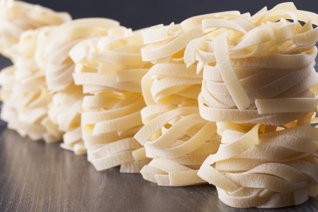 Raw food composition - yellow and brown tagliatelle pasta on a dark background.の写真素材