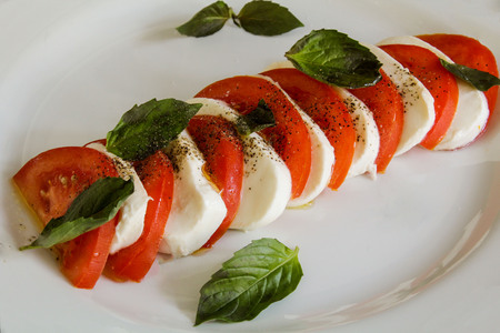 A beautiful delicious salad with tomatoes, mozzarella cheese and basil leaves. Italian foodの写真素材
