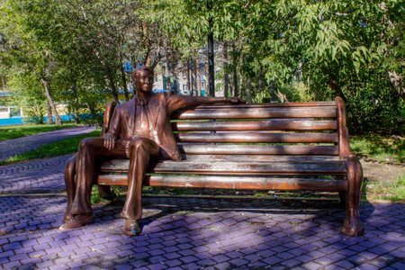 Sculpture of a man sitting on a bench in the parkの写真素材
