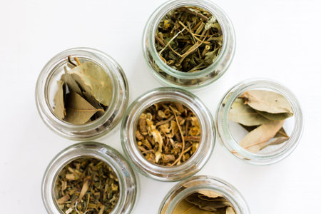 Dried bay leaves in glass jars on white background. Top view.