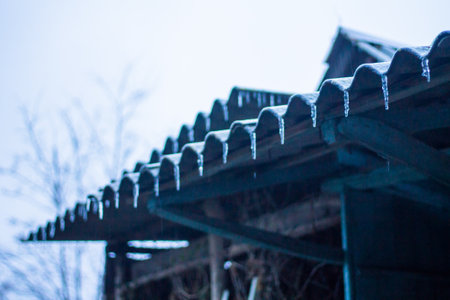 Roof of a wooden house with icicles in the snow.の写真素材