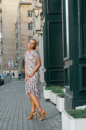 Stylish portrait of woman standing at street in city. Modern style. Beautiful young woman smiling outdoor.の写真素材