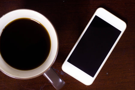 Cup of coffee and smart phone on wood desk