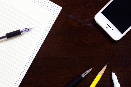Blank book, pen, pencil, and smart phone on old desk