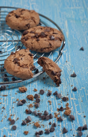 Closeup side view of biscuits with chocolate drops on round iron stand on cracked blue backgroundの写真素材