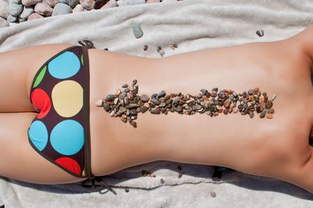 woman's back with stones on it poiting to the seaの写真素材