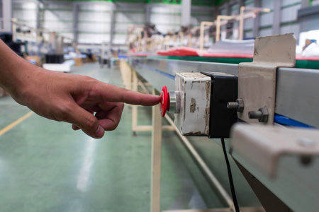 Male hand pushing emergency red stop button.
