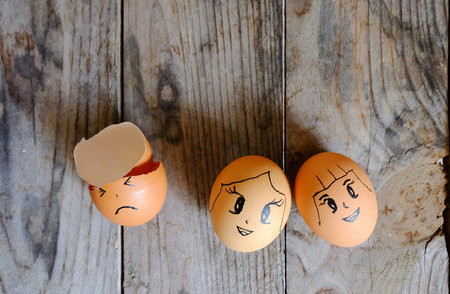 drawing cartoon on three eggs lay on a wooden table, focus on eggs