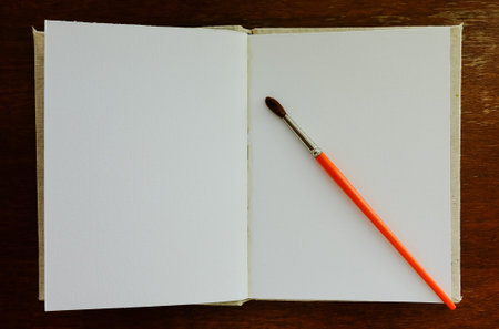 Close-up open blank old notebook on wooden table with one round brushの写真素材