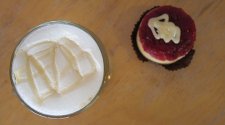 close-up cream of hot coffee and cake on wooden table, selective focus on cream of coffee